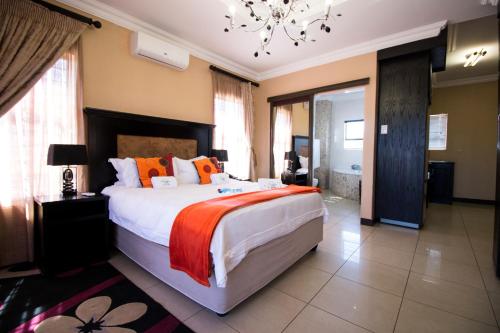 um quarto com uma cama grande e um lustre em The Shamrock Hotel em Polokwane