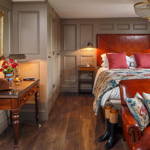 a bedroom with a bed with red pillows and a table at Ffolkes Arms Hotel in Hillington