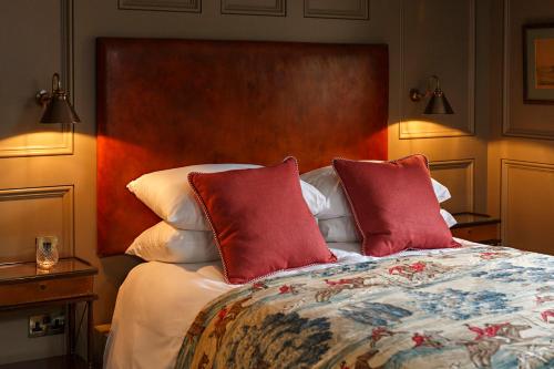 a bedroom with a bed with two red pillows at Ffolkes Arms Hotel in Hillington