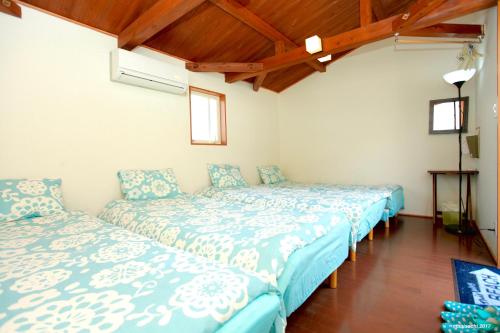 2 łóżka w pokoju z drewnianym sufitem w obiekcie PavilionSurf&Lodge w mieście Shishikui