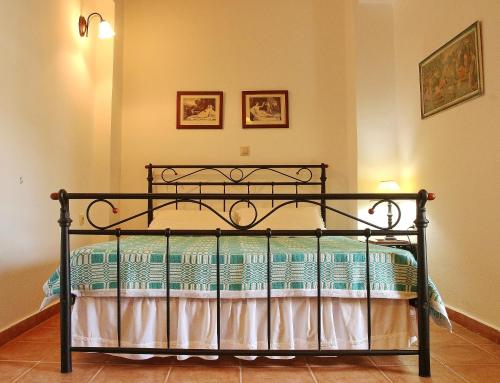 RavdhoúkhaにあるFudulis Villaの壁に2枚の絵が飾られたベッドルームの黒いベッド1台