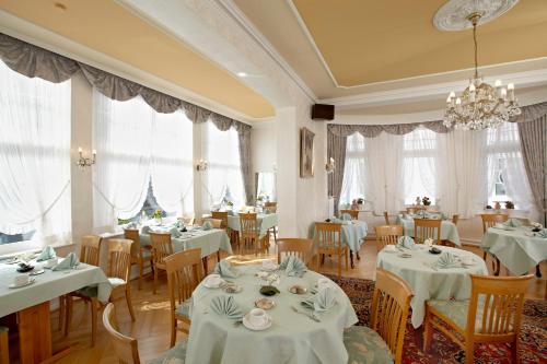 a restaurant with white tables and chairs and windows at HotelHaus Ritter in Bad Pyrmont