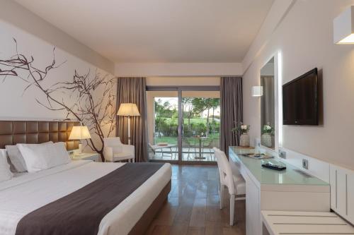 um quarto de hotel com uma cama, uma secretária e uma televisão em Princess Andriana Resort & Spa - Ultra All-Inclusive em Kiotari