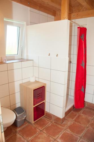 a bathroom with a toilet and a red shower curtain at Hagwaldhof in Niederhofen