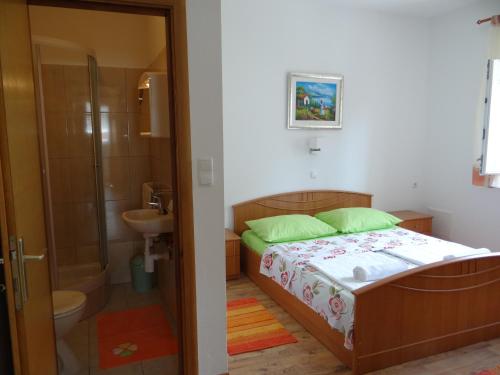 een slaapkamer met een bed en een badkamer met een douche bij Guest house Maria Rosa in Rab