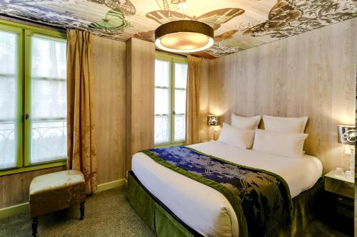 a bedroom with a large bed and windows at Hôtel Le Bellechasse Saint-Germain in Paris