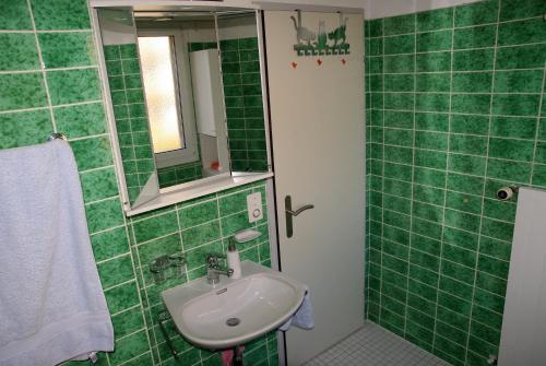 uma casa de banho com azulejos verdes, um lavatório e um espelho. em Ferienwohnung in Davos em Davos