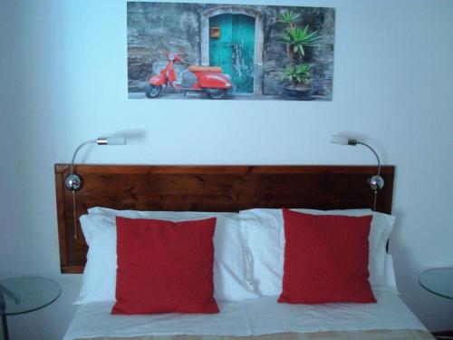 a bed with two red pillows and a picture of a motorcycle at Residenza Le Palme in Caltignaga