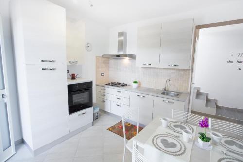 a white kitchen with white cabinets and a sink at Le Zagare in Lascari