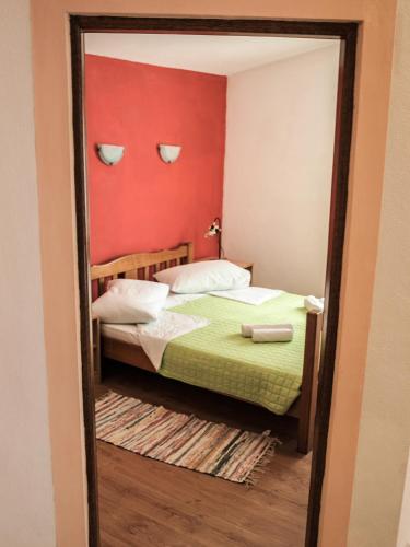 a mirror reflecting a bedroom with a bed and a red wall at Apartment Pletikosic in Kaštela
