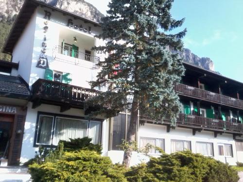 a large white building with a tree in front of it at Hotel Regina Delle Dolomiti in Panchia