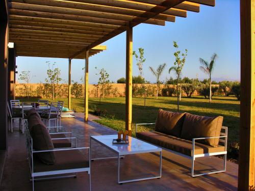 a patio with couches and tables with a view of a field at Villa Jardins D'Isa in Marrakech