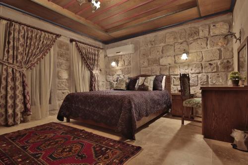 a bedroom with a bed and a stone wall at Guzide Cave Hotel in Göreme