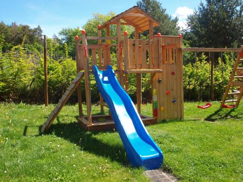 une aire de jeux avec toboggan bleu et structure en bois dans l'établissement Kerschbamerhof im Süden Südtirols, à Cortaccia sulla Strada del Vino