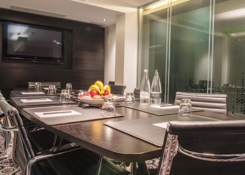 a dining room with a table with chairs and a television at The Vincent Hotel in Southport