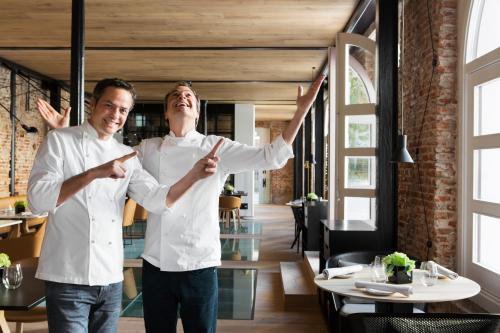 two men standing in a restaurant with their hands up at Palacio de los Duques Gran Meliá - The Leading Hotels of the World in Madrid