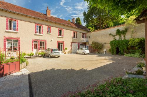 un parcheggio di fronte a un edificio con due auto di Chambres d'hôtes - Domaine Gigou a La Chartre-sur-le-Loir