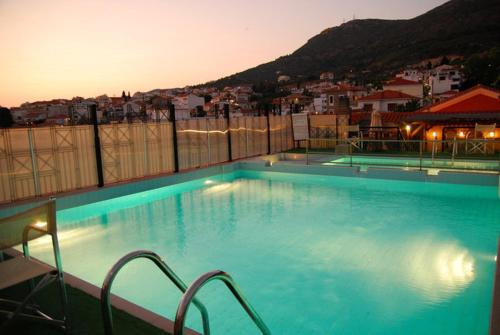 a large swimming pool with a city in the background at Aeolis Hotel in Samos