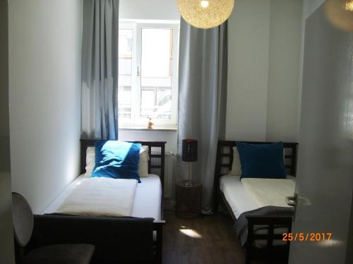 two beds with blue pillows in a room with a window at Munich Aparthotel in Munich
