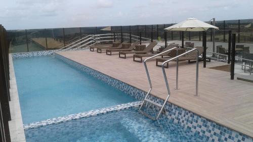 una piscina con bancos y una sombrilla en un edificio en Intercity Suape Costa Dourada en Cabo de Santo Agostinho