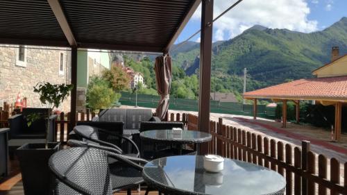 a patio with tables and chairs and mountains in the background at Hotel La Cuna del Sella in Oseja de Sajambre