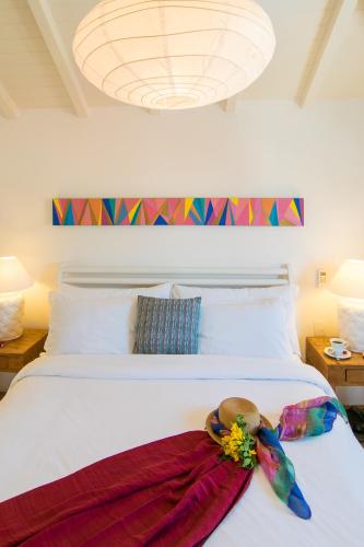 a white bed with a hat on top of it at La Chimère Buzios Essence in Búzios