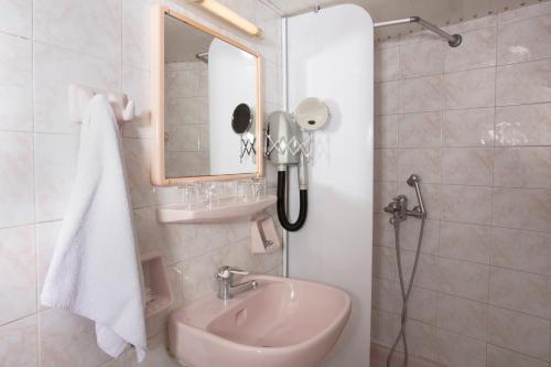 a white bathroom with a sink and a mirror at Xenophon Hotel in Athens