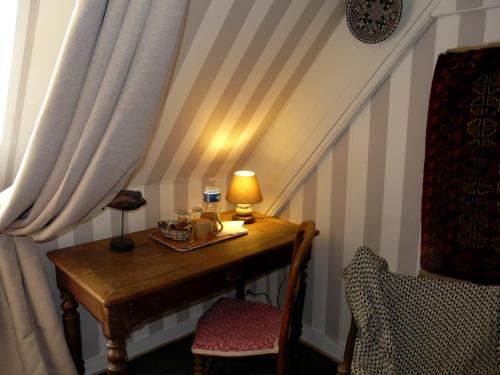einen Schreibtisch mit einer Lampe und einem Stuhl in einem Zimmer in der Unterkunft Manoir Tregont Mab in Quimper