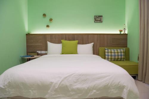 a bedroom with a large white bed and a green chair at Mysig in Luodong