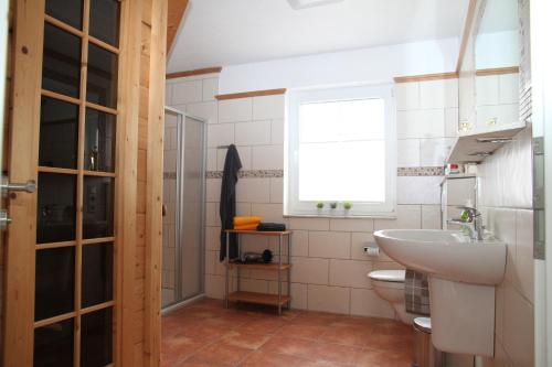 baño con lavabo y aseo y ventana en Skippersin5, en Greetsiel