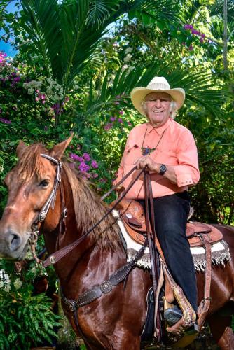 a man in a cowboy hat riding a horse at Banana Bank Lodge & Jungle Horseback Adventures in Belmopan