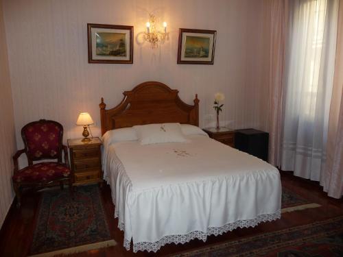 a bedroom with a white bed and a chair at Pension Lorea in San Sebasti&aacute;n