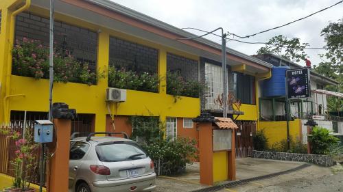 a yellow building with a car parked in front of it at Hotel Villa Prats in Manuel Antonio