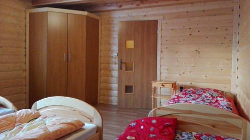 a bedroom with two beds and a wooden wall at Agroturystyka pod Pstragiem in Zawoja