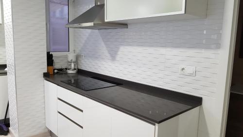 cocina con armarios blancos y encimera negra en Apartamento Jardín de Ayora en Valencia