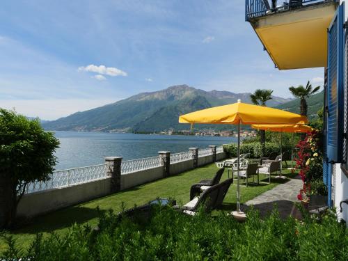 a patio with chairs and an umbrella next to the water at Residence Leggeri in Domaso