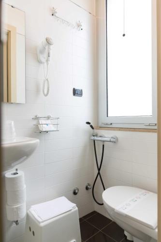 a white bathroom with a toilet and a sink at Hotel Miramare Dipendenza in Pineto