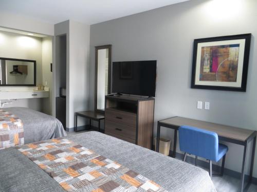 a hotel room with two beds and a flat screen tv at Haven Inn & Suites willowbrook in Houston