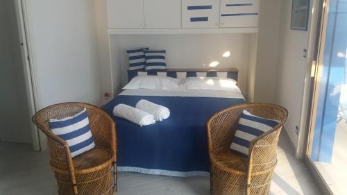 a bedroom with a blue and white bed with two chairs at Ipanema Suite in Giardini Naxos