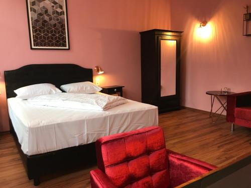 a bedroom with a bed and a red chair at SmartHotel Mystique Self check-in in Bad Homburg vor der Höhe