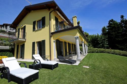 a yellow house with white chairs on the lawn at Casa Ketty in Bellagio