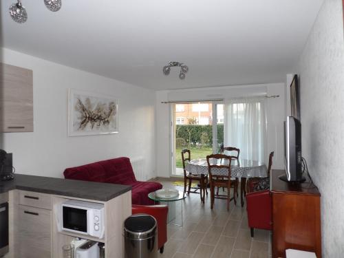 a kitchen and living room with a red couch and a table at Clos Fleuri in Berck-sur-Mer