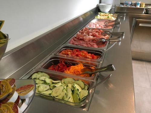 Un buffet con varias bandejas de comida en un mostrador. en Villa Franca, en Nago-Torbole