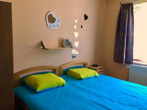 a bedroom with a blue bed with two green pillows at Le Valdine in Jemeppe