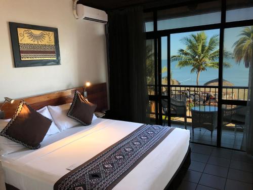 a bedroom with a bed with a view of the ocean at Smugglers Cove Beach Resort & Hotel in Nadi