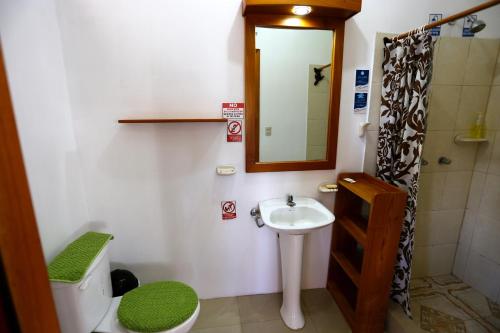 a bathroom with a sink and a toilet and a mirror at The Galapagos Pearl B&B in Puerto Ayora