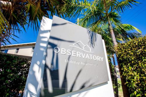 a large white sign on top of a palm tree at The Observatory Self Contained Apartments in Coffs Harbour