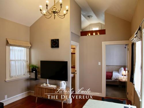 a living room with a television and a chandelier at The Devereux Boutique Hotel in Auckland