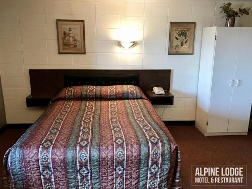 a hotel room with a bed and a refrigerator at Alpine Lodge Motel & Restaurant in Grande Cache