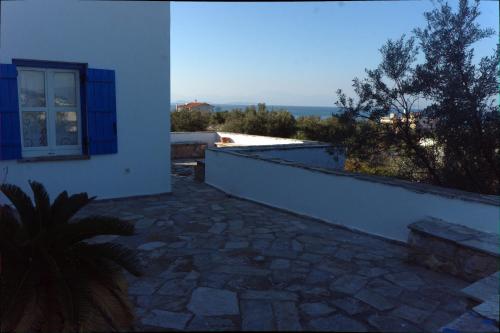 a white building with a window and a stone patio at Aiolos in Skala